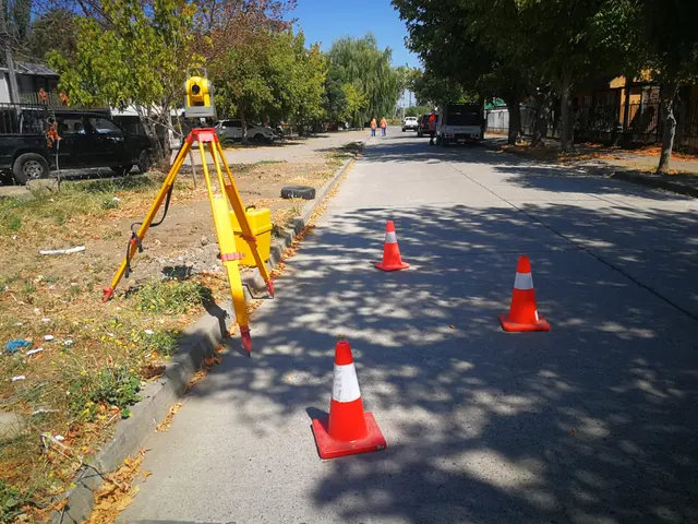 Estación total sobre trípode y conos de seguridad en una calle