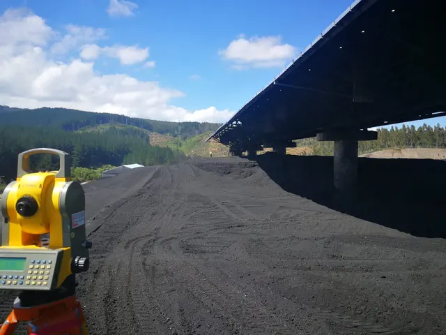 Estación total frente a una parva de carbón