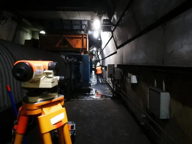 Nivel óptico sobre trípode en un túnel industrial